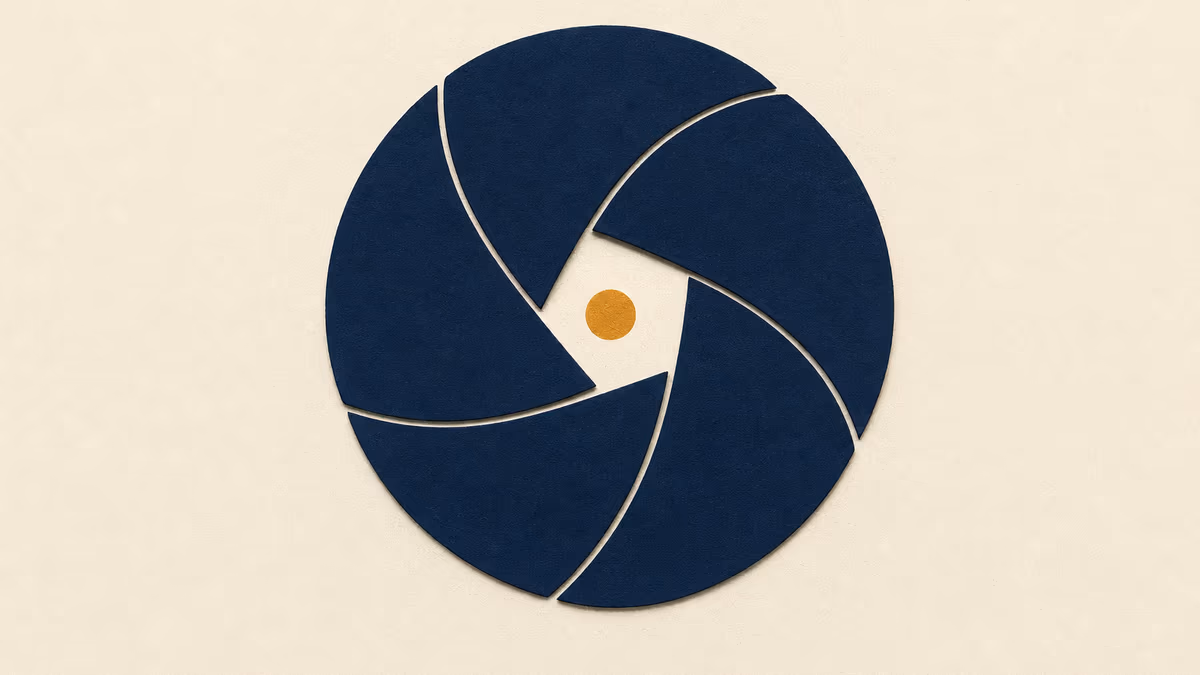 A stylized navy camera-aperture iris closes inward over a warm ivory background, leaving a small amber circle of light at the center.